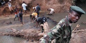 Workers and a military member of an African nation working in a stream